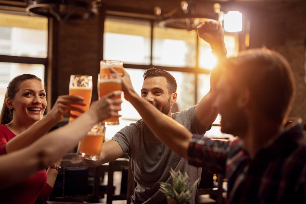 grupo-de-jovens-felizes-brindando-com-cerveja-e-se-divertindo-em-um-pub